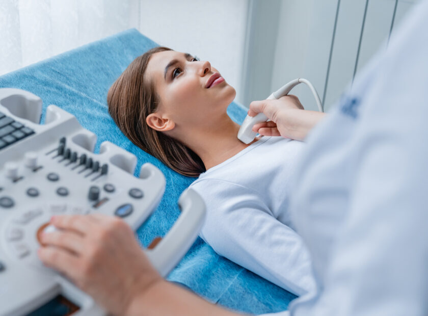 Woman getting her neck examined by female doctor using ultrasound scanner at modern clinic